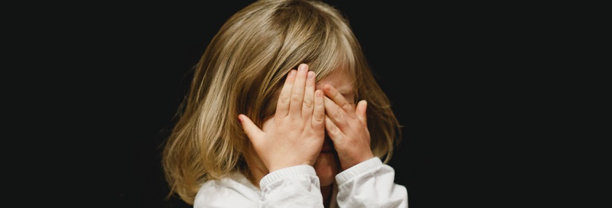 Sad, scared girl, shields her eyes - child protection